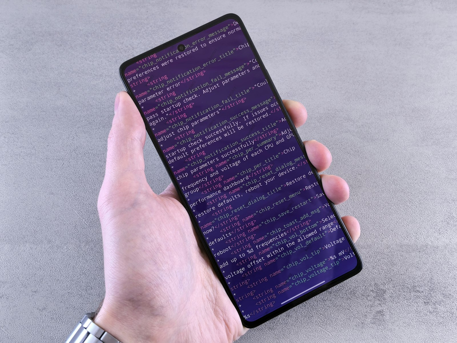 Main tenant un smartphone affichant du code